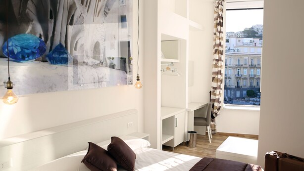 A modern hotel room with a large bed, a desk, and a view of the city. - DIMORA DIAMANTE - ZAFFIRO ROOM                                    (Napoli)
