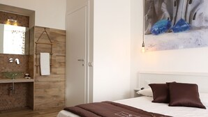 A bedroom with a bed, pillows, a bedside table, a lamp, and a suitcase. - DIMORA DIAMANTE - ZAFFIRO ROOM                                    (Napoli)