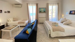 Hotellihuone, jossa on kaksi sänkyä, sohva, pieni pöytä ja näkymä ulos.