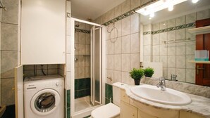 A bathroom with a washing machine, toilet, shower, sink, and a mirror. - Bright apartment, 2nd floor, two rooms in the port of Empuriabrava (Empuriabrava)