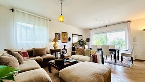 Ein Wohnzimmer mit einer Sofagarnitur, einem Couchtisch und einem Essbereich mit Tisch und Stühlen.