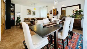 Ein Essbereich mit einem dunklen Holztisch, weißen Stühlen und einem gemusterten Teppich.