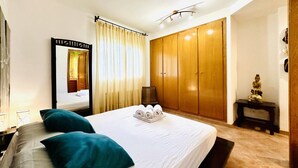 Ein Hotelzimmer mit Bett, Kleiderschrank, Spiegel und Statue.