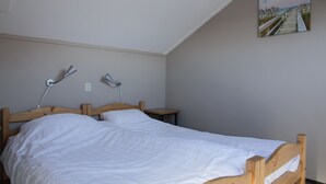 A single bed with a wooden headboard and footboard, two bedside lamps, and a small bedside table.