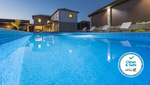 Ein Schwimmbecken mit Liegestühlen und einem Gebäude im Hintergrund.