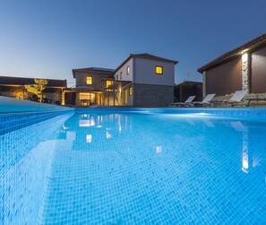 A swimming pool with lounge chairs and a building in the background.