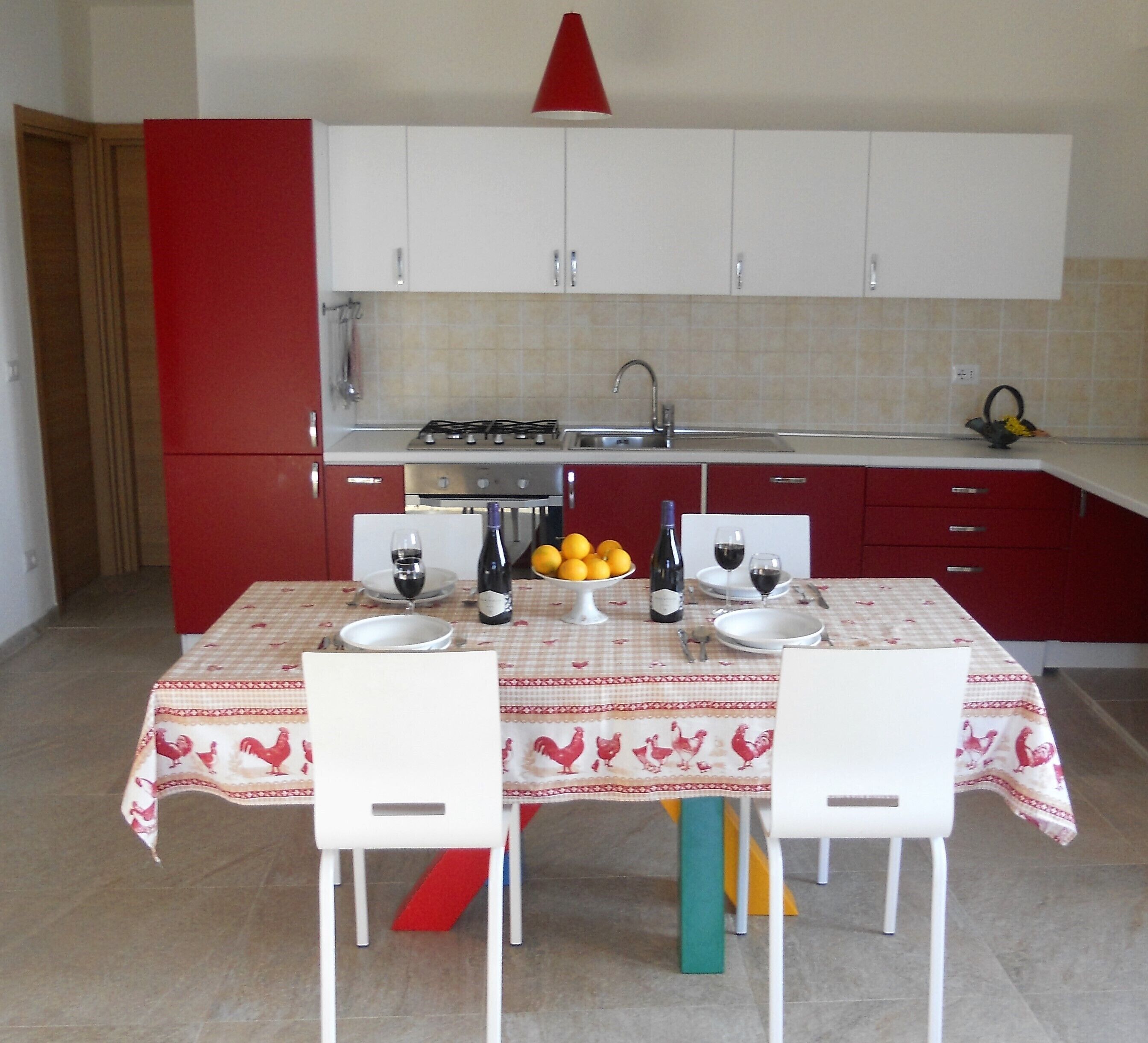 A kitchen with a dining table set for two, a gas stove, and a sink.