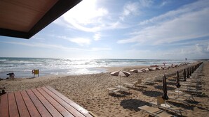Une plage avec des terrasses en bois, des parasols et des chaises longues.
