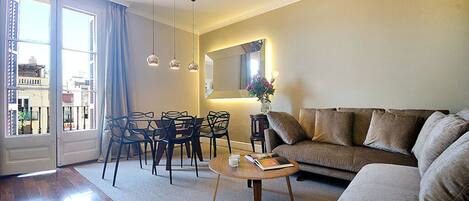 Un salon comprenant un canapé, des fauteuils, une table basse et un coin repas avec des chaises et une table.