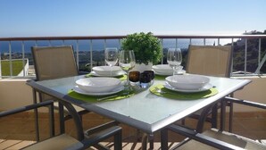 A table set for two with plates, glasses, and a small potted plant on a balcony overlooking a scenic view. - Apartment with Sea Views and Sunlit Terraces (Marbella)