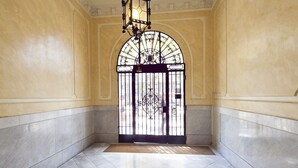 A spacious hallway with a large arched doorway, a tiled floor, and a hanging light fixture. - Three bedroom apartment Diagonal - You Stylish (Barcelona)
