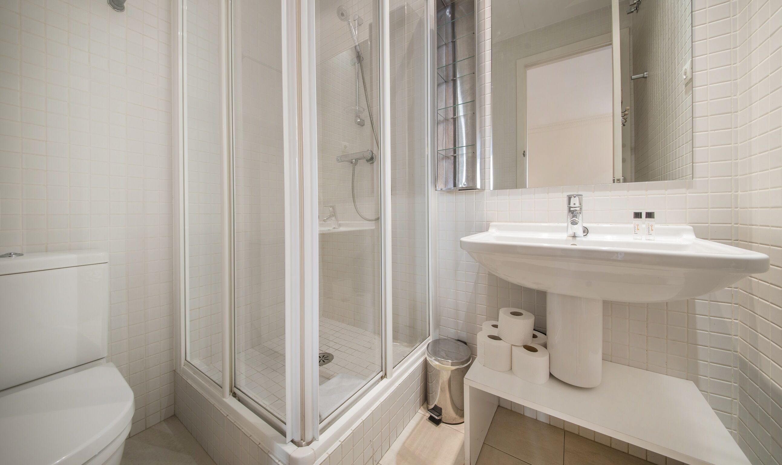 A modern bathroom with a glass-enclosed shower, a white sink, and a toilet.