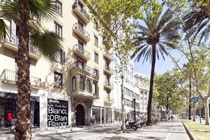 Vista de la calle con un edificio que tiene balcones y un letrero que dice 'Blanco'.