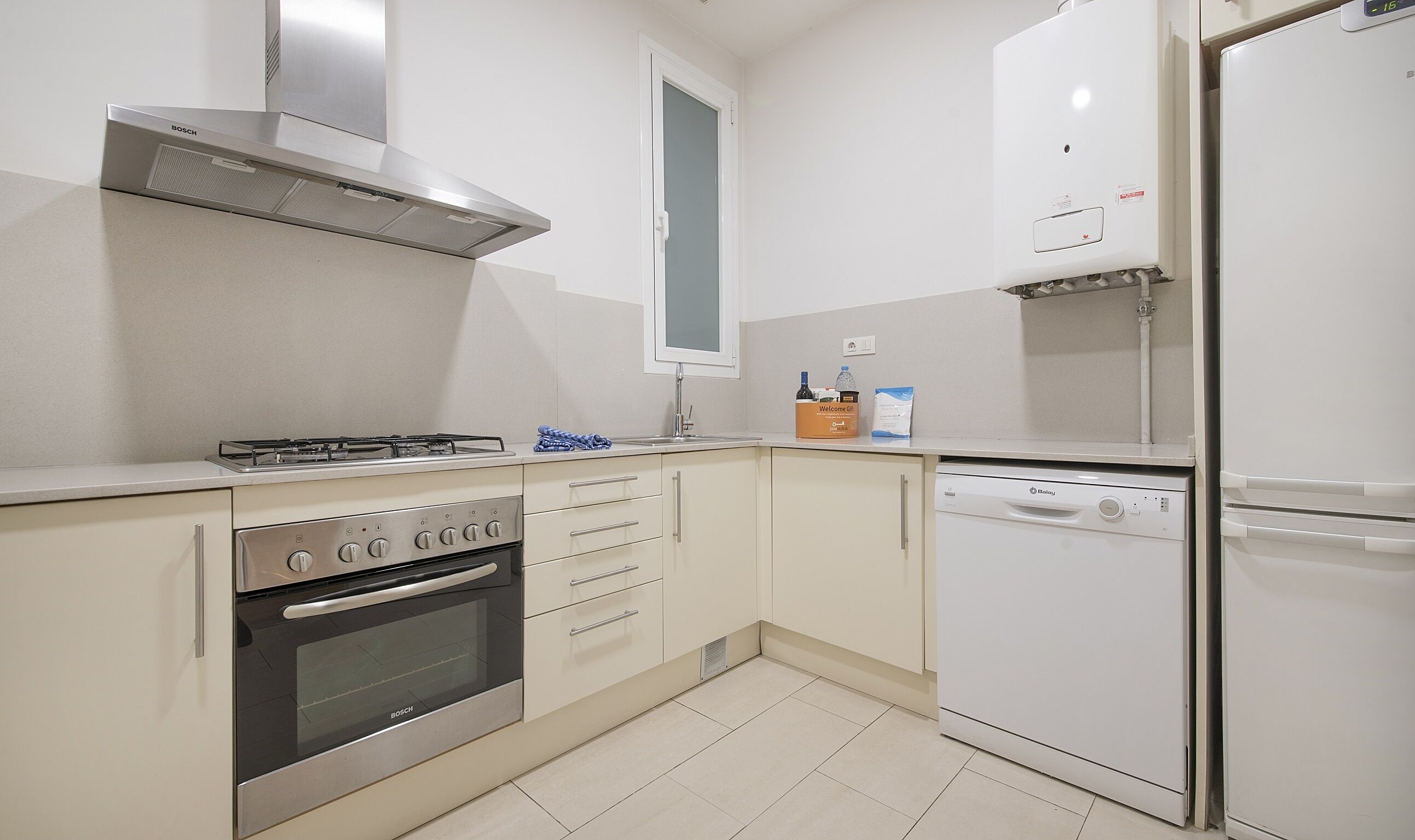 A compact kitchen with a Bosch gas stove, oven, and dishwasher, and a white refrigerator.