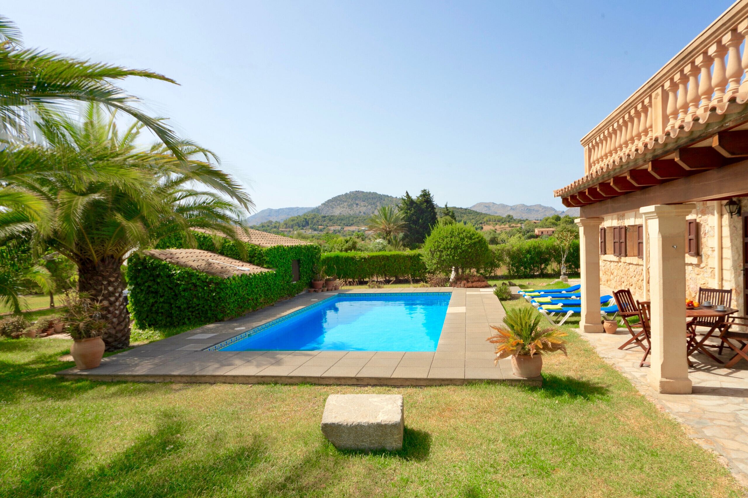Una piscina con una vista despejada del paisaje circundante, incluyendo colinas y un edificio con tejado de baldosas.
