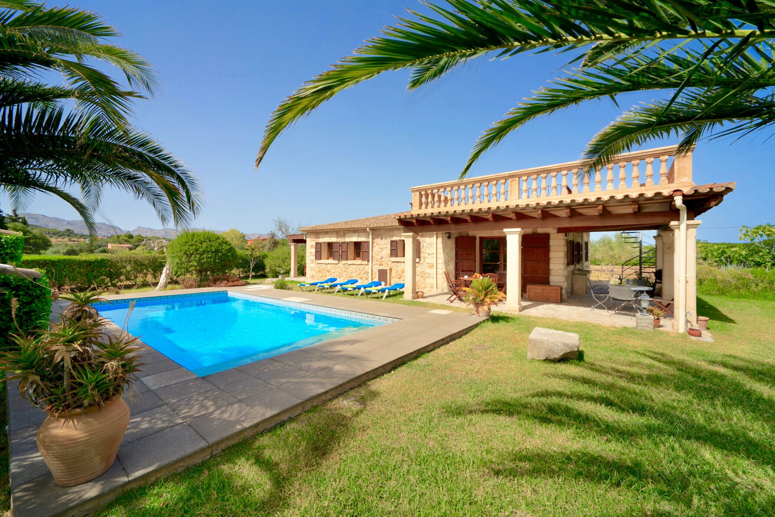 Una casa con piscina, patio cubierto y césped.