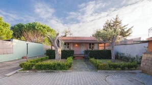 Una casa con techo de tejas, camino de entrada pavimentado y jardín cuidado con setos y árboles.