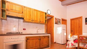 Una cocina con armarios de madera, una estufa blanca, un lavamanos y un refrigerador.