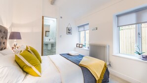 Ein Schlafzimmer mit Bett, Nachttisch, Lampe und einem Fenster mit Blick auf einen Zaun.