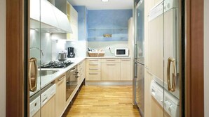 Una cocina estrecha con armarios de madera, un microondas, una estufa y un lavavajillas.