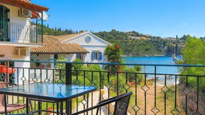 A terrace with a table and chairs, overlooking a coastal area with buildings and boats.