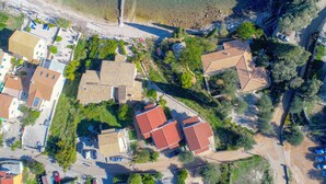 An aerial view of a coastal residential area with houses, a beach, and a lighthouse.
