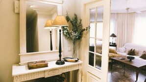 Una habitación con un espejo grande, una lámpara, un florero con plantas y un sofá.