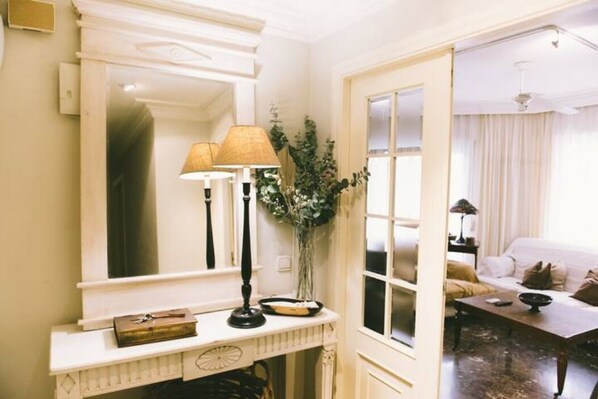 A room with a large mirror, a lamp, a vase with plants, and a sofa. - Central, bright and close to the beach (alicante)