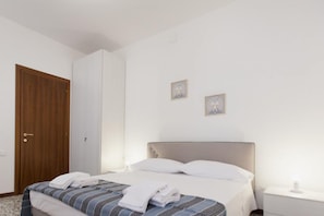 A neatly made bed with white linens, a wooden door, and two small framed pictures on the wall. - Ca' Riolfo, Rialto Bridge (Venice)