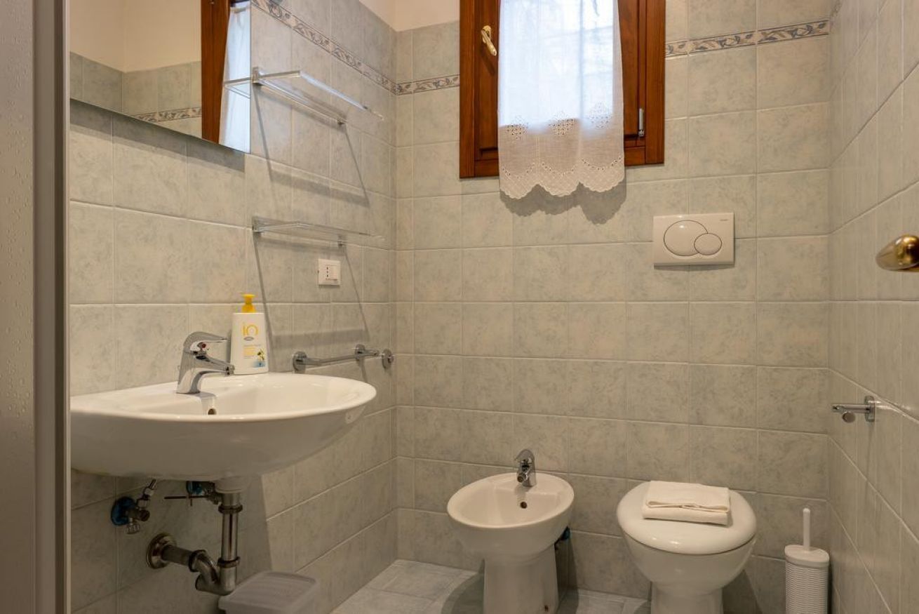 A bathroom with a sink, bidet, toilet, and a towel rack.