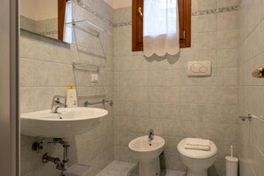 A bathroom with a sink, bidet, toilet, and a towel rack.