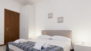 A neatly made bed with white linens, a wooden door, and two small framed pictures on the wall. - Ca' Riolfo, Rialto Bridge (Venice)