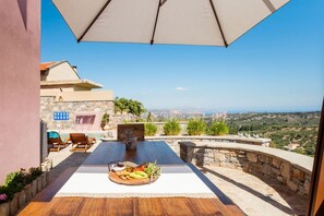 Une terrasse avec une piscine, des sièges d’extérieur et une table où sont servis des plats.