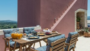 Een terras met een ontbijttafel, compleet met eieren, fruit en gebak.