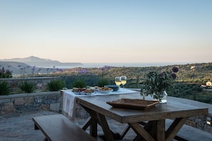 An outdoor dining area with a table set for two, overlooking a scenic landscape.