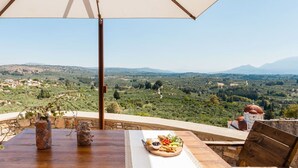 Ein Tisch mit Blick auf eine gebirgige Landschaft, ein Holztisch und ein Steingefäß.