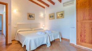 A bedroom with two beds, wooden beams, white walls, and framed pictures.