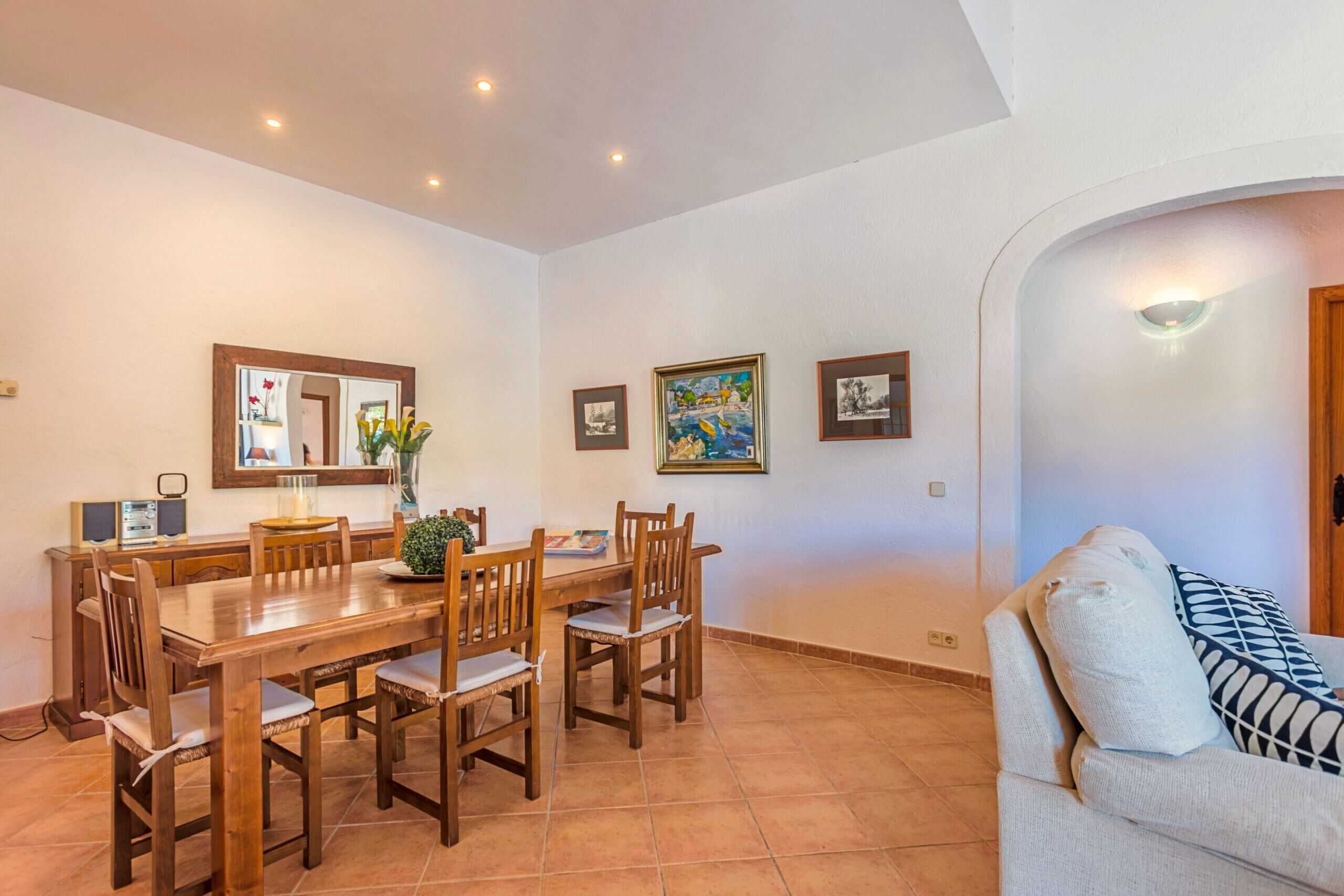 Un comedor con una mesa y sillas de madera, un florero con flores y cuadros en la pared.