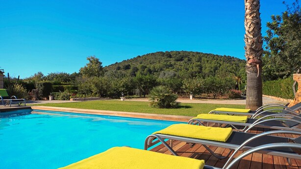 A swimming pool with lounge chairs and a view of a hill.
