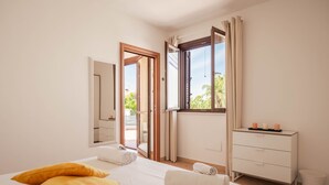 Une chambre d’hôtel avec un lit, une commode, un miroir et une fenêtre avec des rideaux.