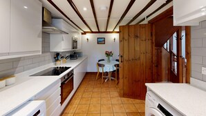 A compact kitchen with white cabinetry, a built-in oven, and a wooden door leading to another room. - Courtyard cottage with extensive private grounds and free WiFi (Swansea)