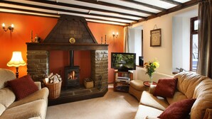 A cozy living room with a stone fireplace, a television, and comfortable seating. - Courtyard cottage with extensive private grounds and free WiFi (Swansea)
