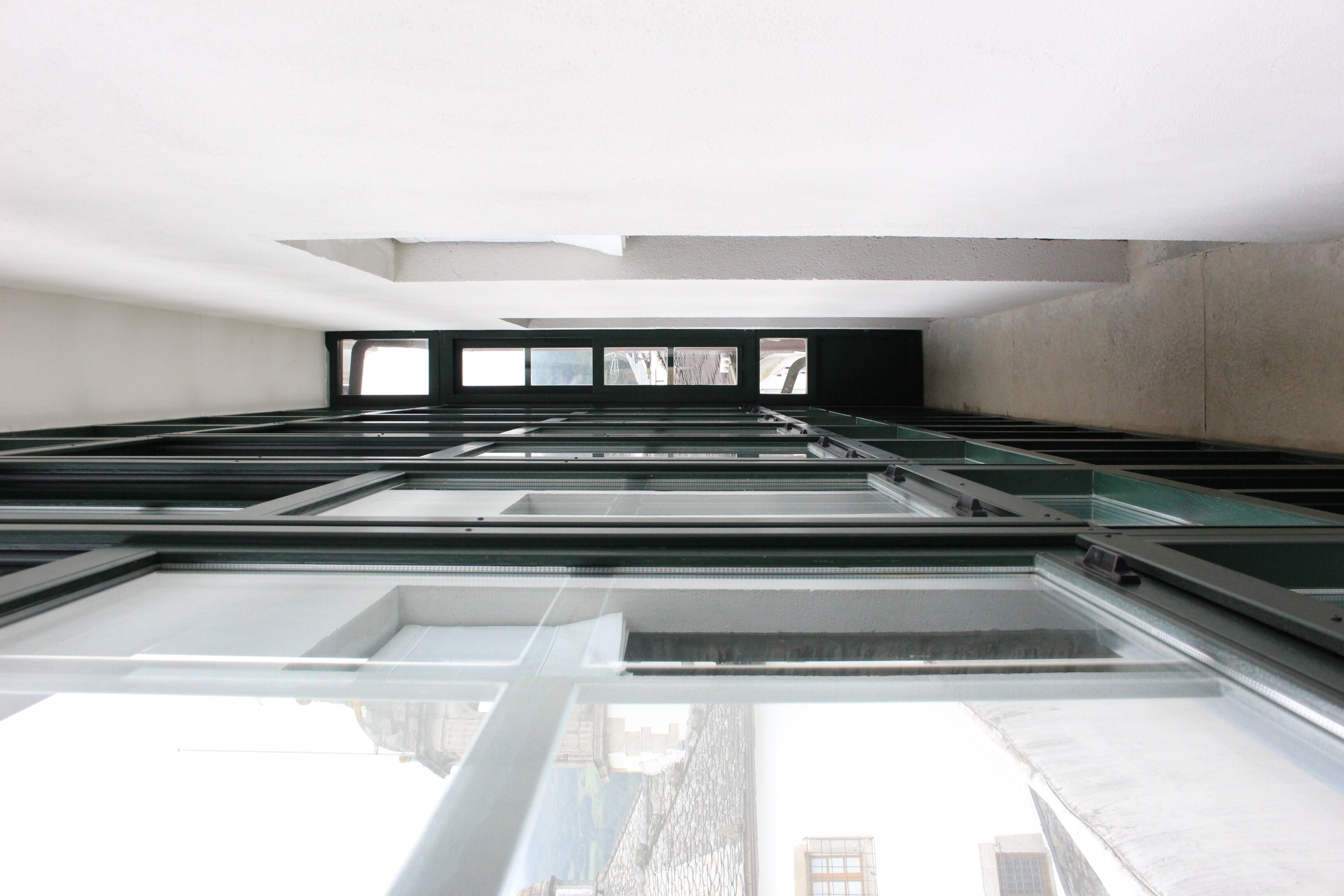 Un intérieur moderne avec un plafond haut, des fenêtres de toit et une vue sur l’extérieur.