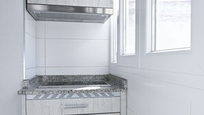A kitchen with white cabinetry, a stainless steel range hood, and a granite countertop.