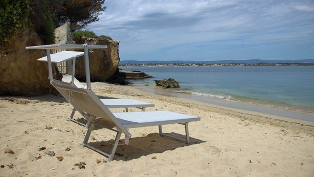 A beach with two white lounge chairs and a rocky cliff. - Independent villa on the sea (Isola)