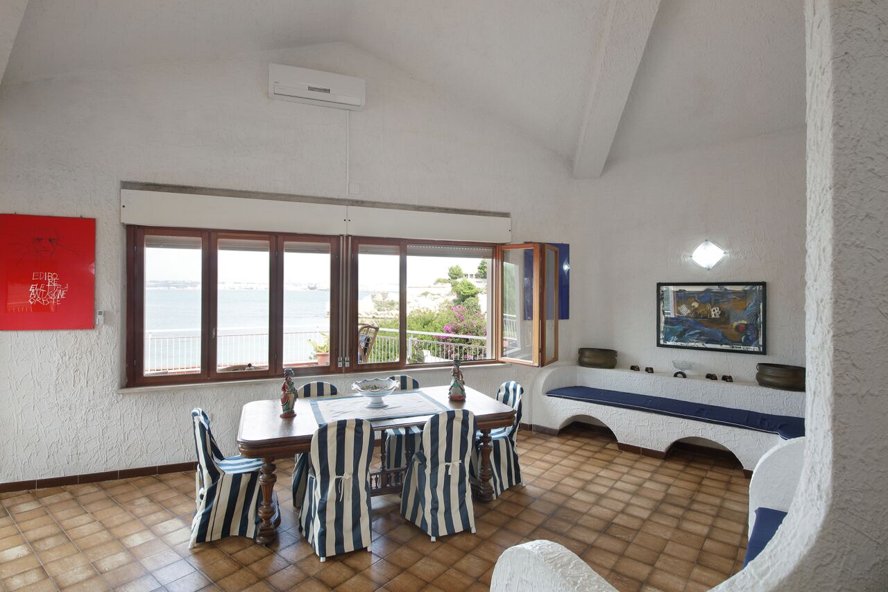 A dining area with a large window, a table with chairs, and a bench along the wall.