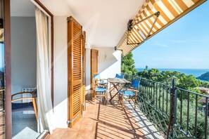 A balcony with a wooden table and chairs, a view of the sea, and a railing. - Antora C (Calella de Palafrugell)