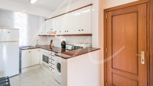 Une cuisine avec des armoires blanches, un plan de travail en bois, un lave-linge et une porte en bois.