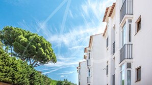 Une rangée de bâtiments blancs dotés de balcons, sous un ciel d’un bleu limpide.
