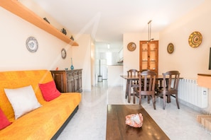 A living room with a sofa, a coffee table, and a dining area with chairs and a table.
